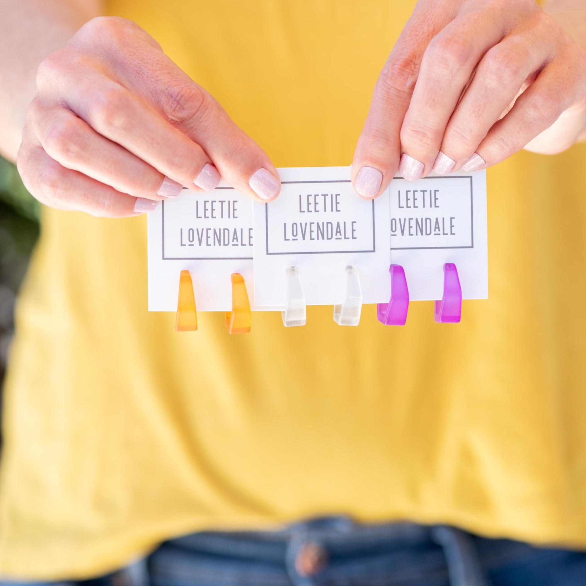 tapered hex hoop earrings in hands with pink fingernails