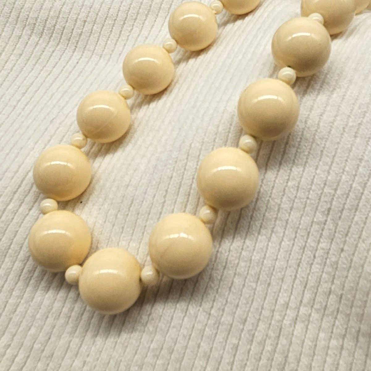 Beige beaded necklace on a textured beige surface