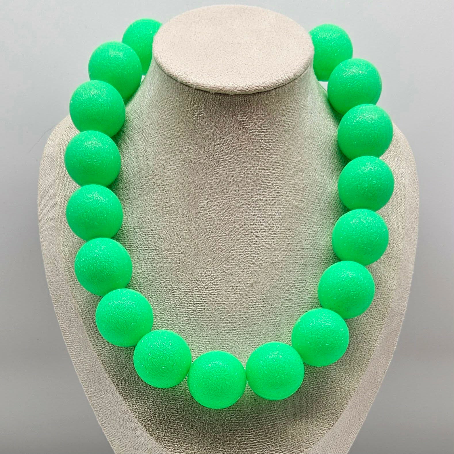 Necklace with green beads on a gray stand