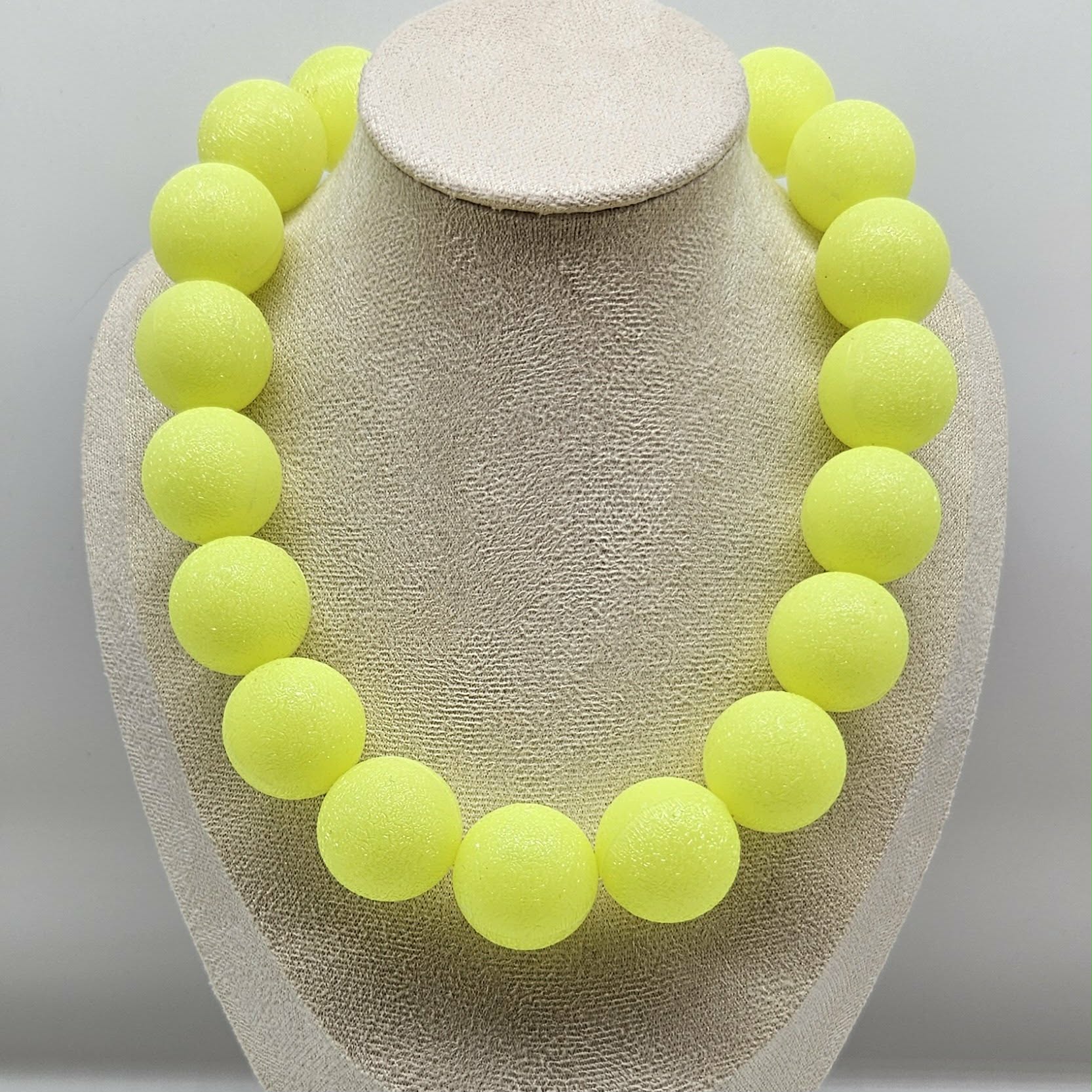 Neon yellow bead necklace on a beige jewelry display
