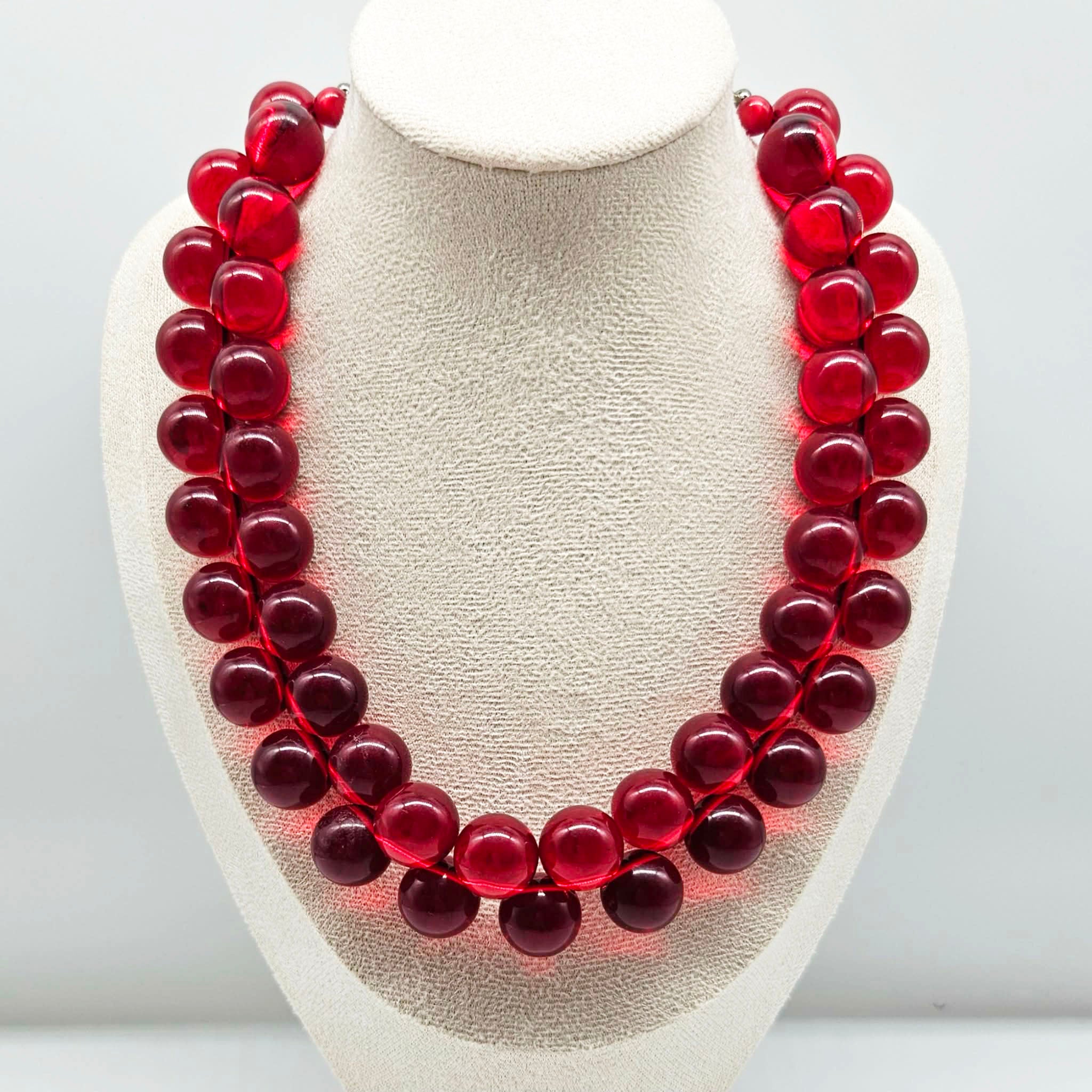 Red cluster beaded necklace on a bust.