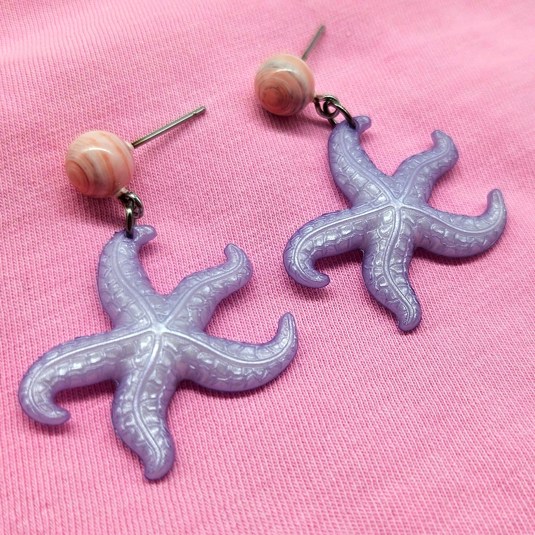 Starfish-shaped earrings on a pink background
