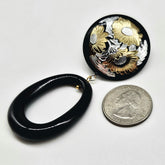 Black and gold floral earrings with a quarter for scale on a white background