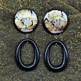Pair of earrings with floral designs on a textured fabric background