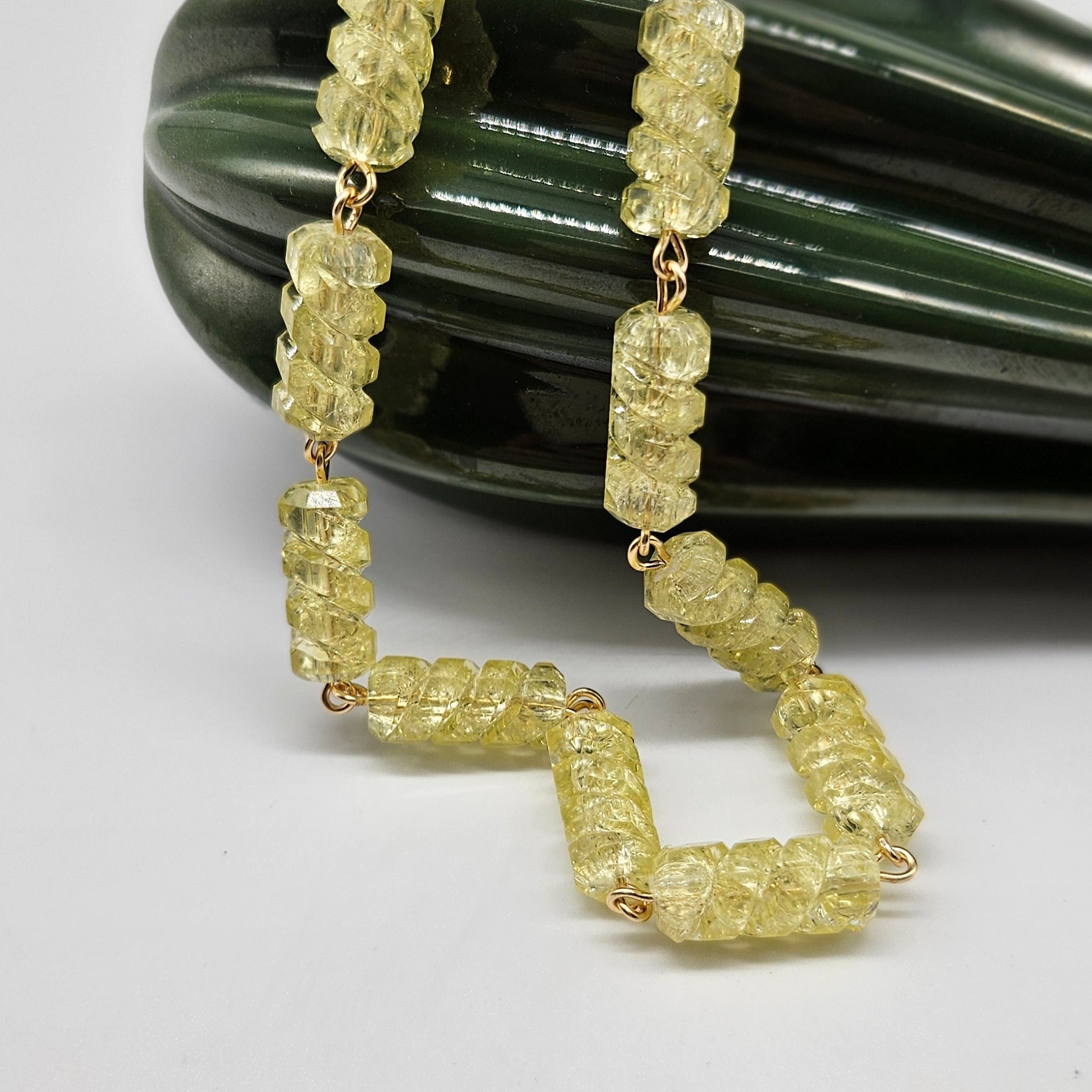 Yellow lucite necklace with gold wiring on a white and green background