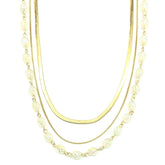 Three-strand necklace with gold chains and clear-colored beads on a white background
