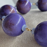 Close-up of a necklace with purple beads on a textured surface