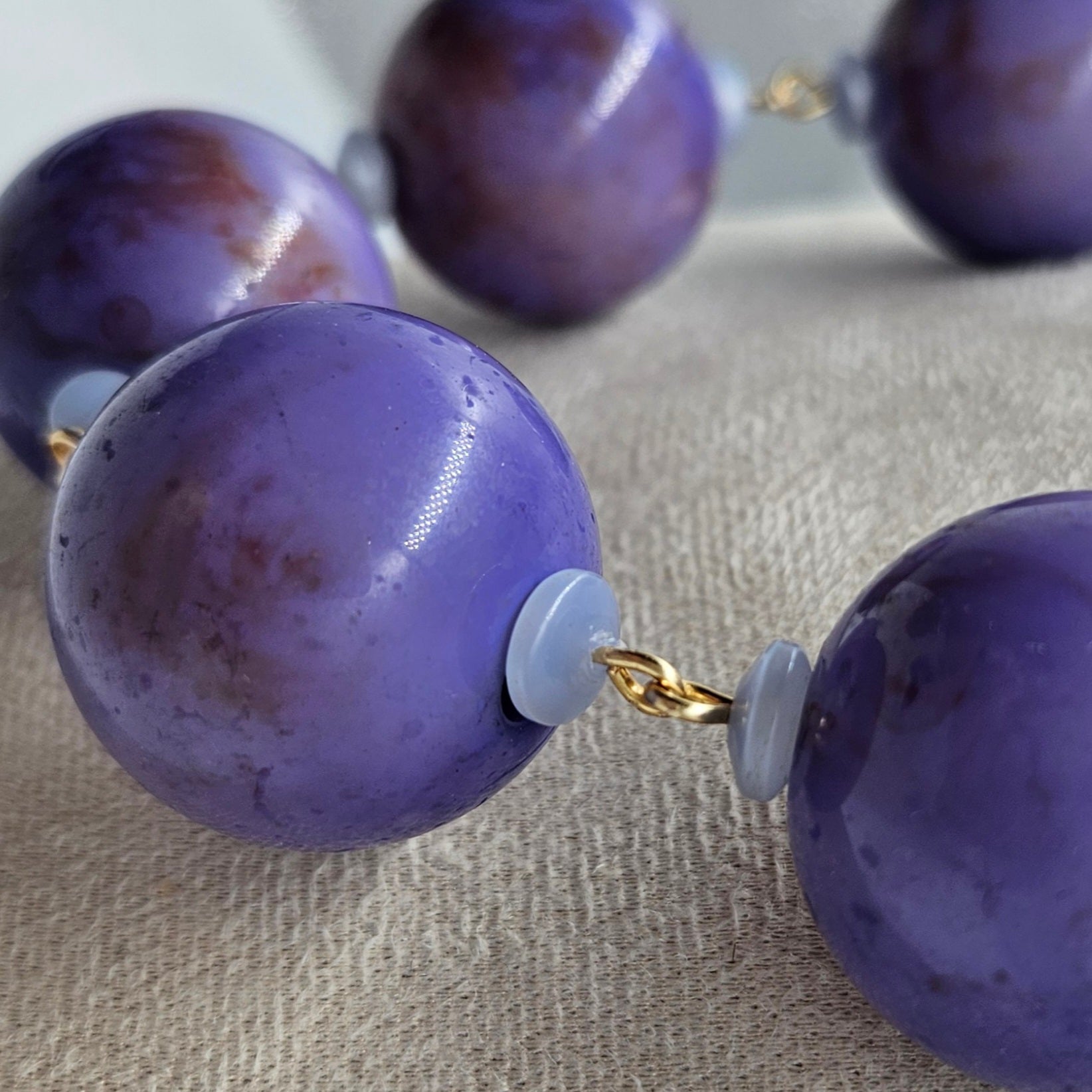 Close-up of a necklace with purple beads on a textured surface
