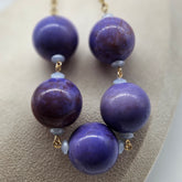 Purple beaded necklace on a beige surface