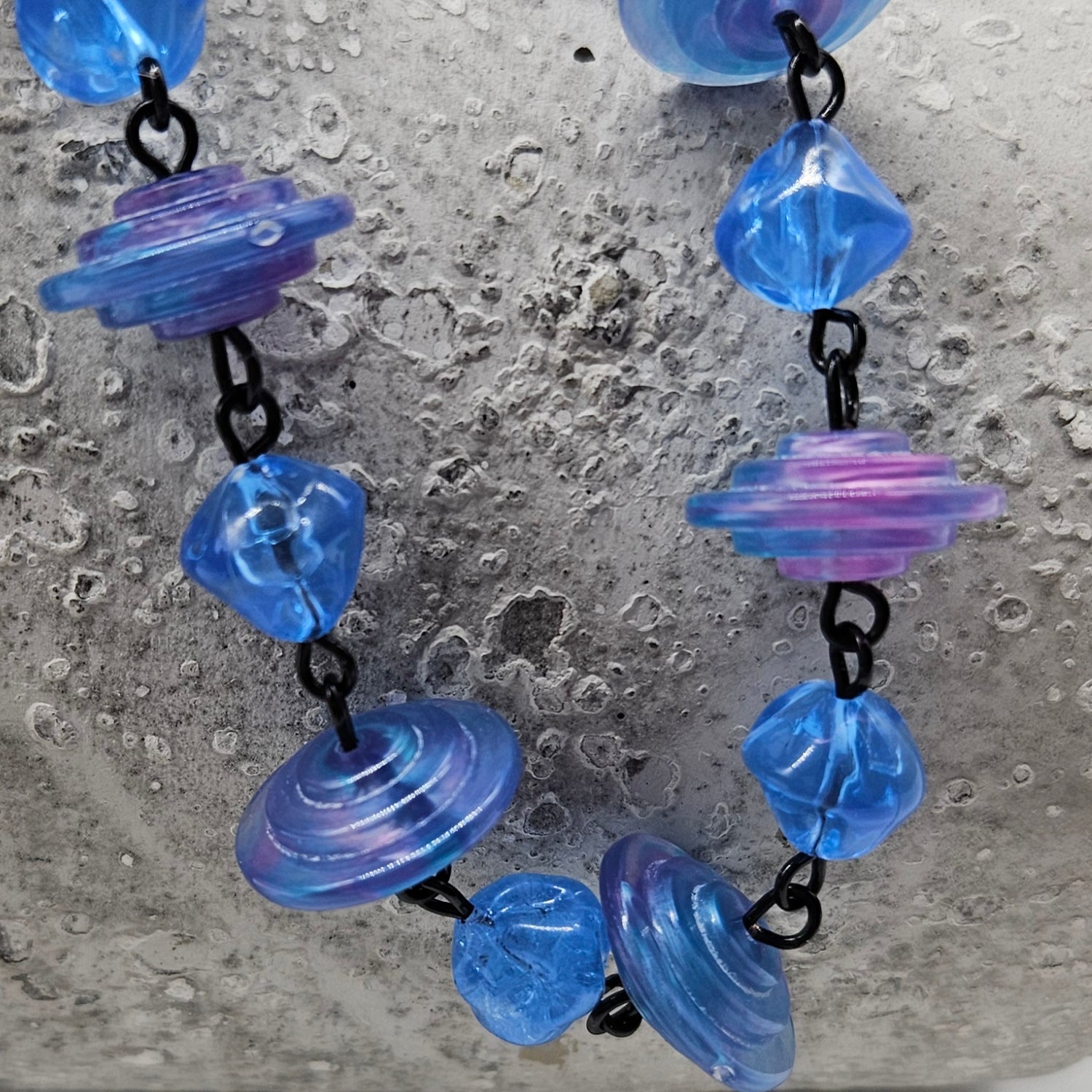 Necklace with blue and purple lucite beads on a textured surface