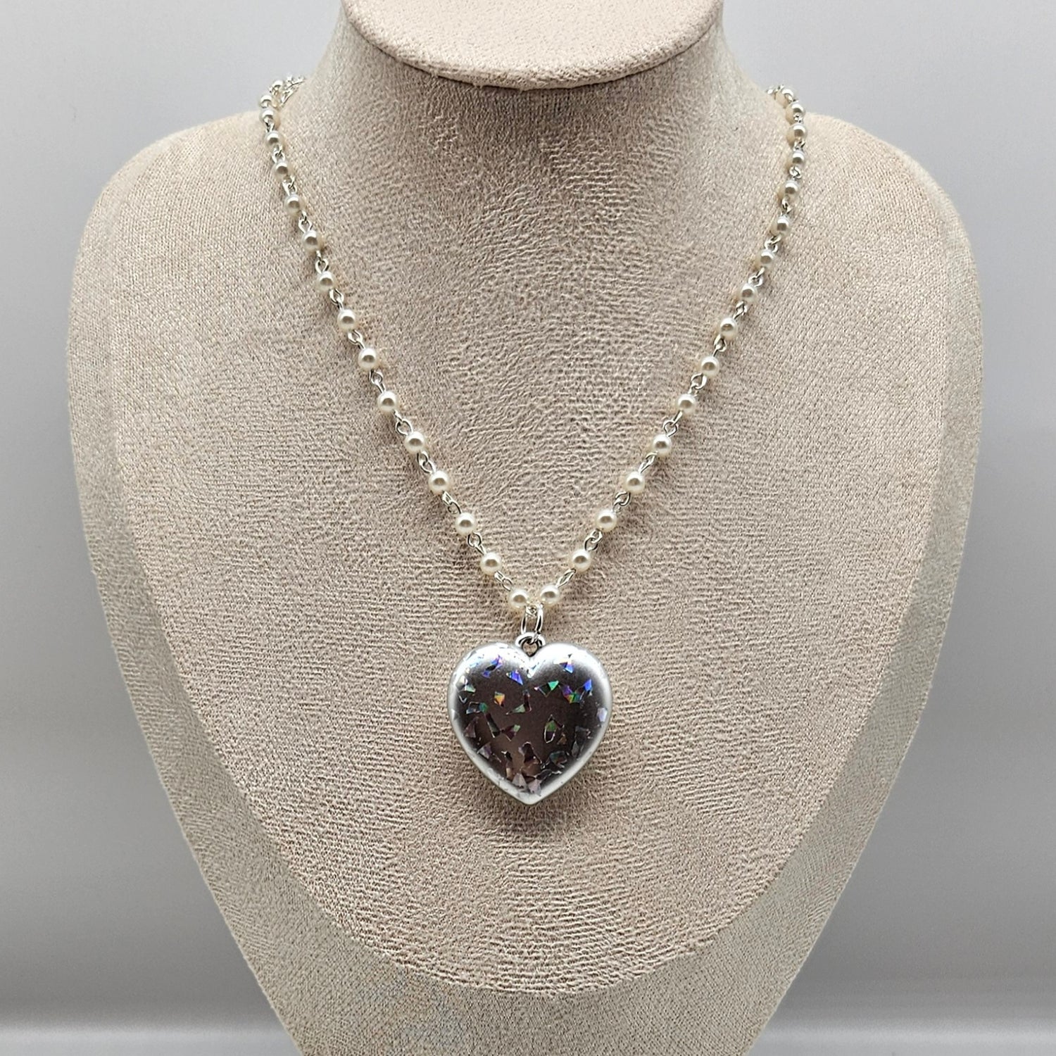 Necklace with a heart-shaped pendant on a mannequin bust against a gray background