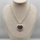Necklace with a heart-shaped pendant on a mannequin bust against a gray background