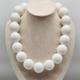 White spherical necklace on a beige mannequin bust against a gray background