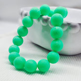 Green beaded necklace on a textured surface with a blurred background