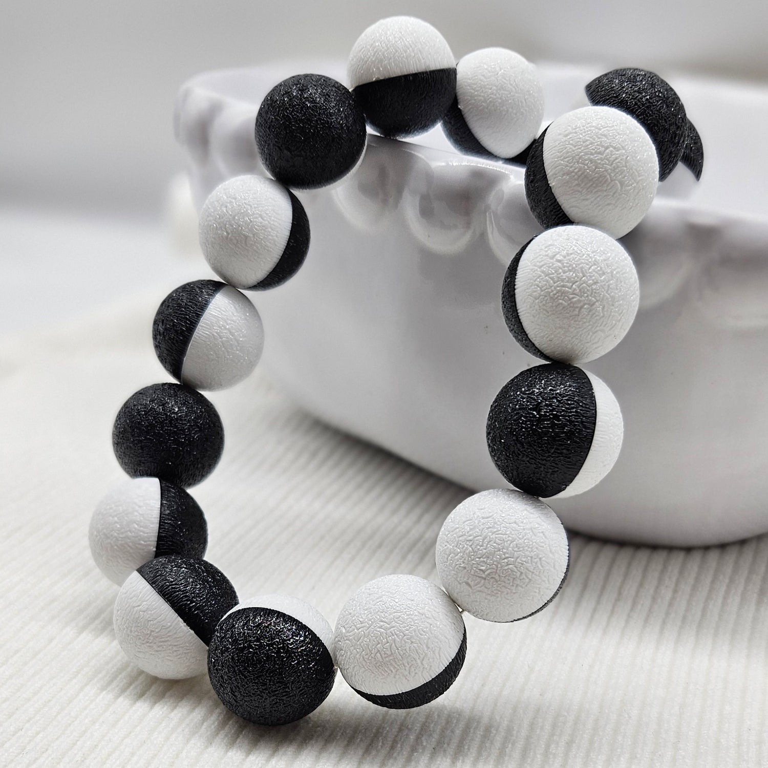 Black and white beaded necklace laid on a white bowl.