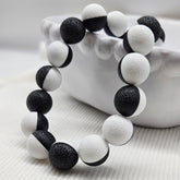 Black and white beaded necklace laid on a white bowl.