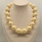 Necklace with large cream-colored beads on a mannequin bust against a neutral background