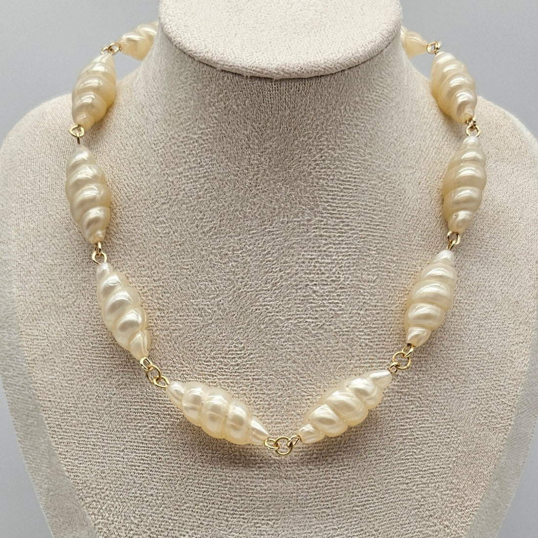 Lucite pearl necklace on a mannequin bust against a neutral background