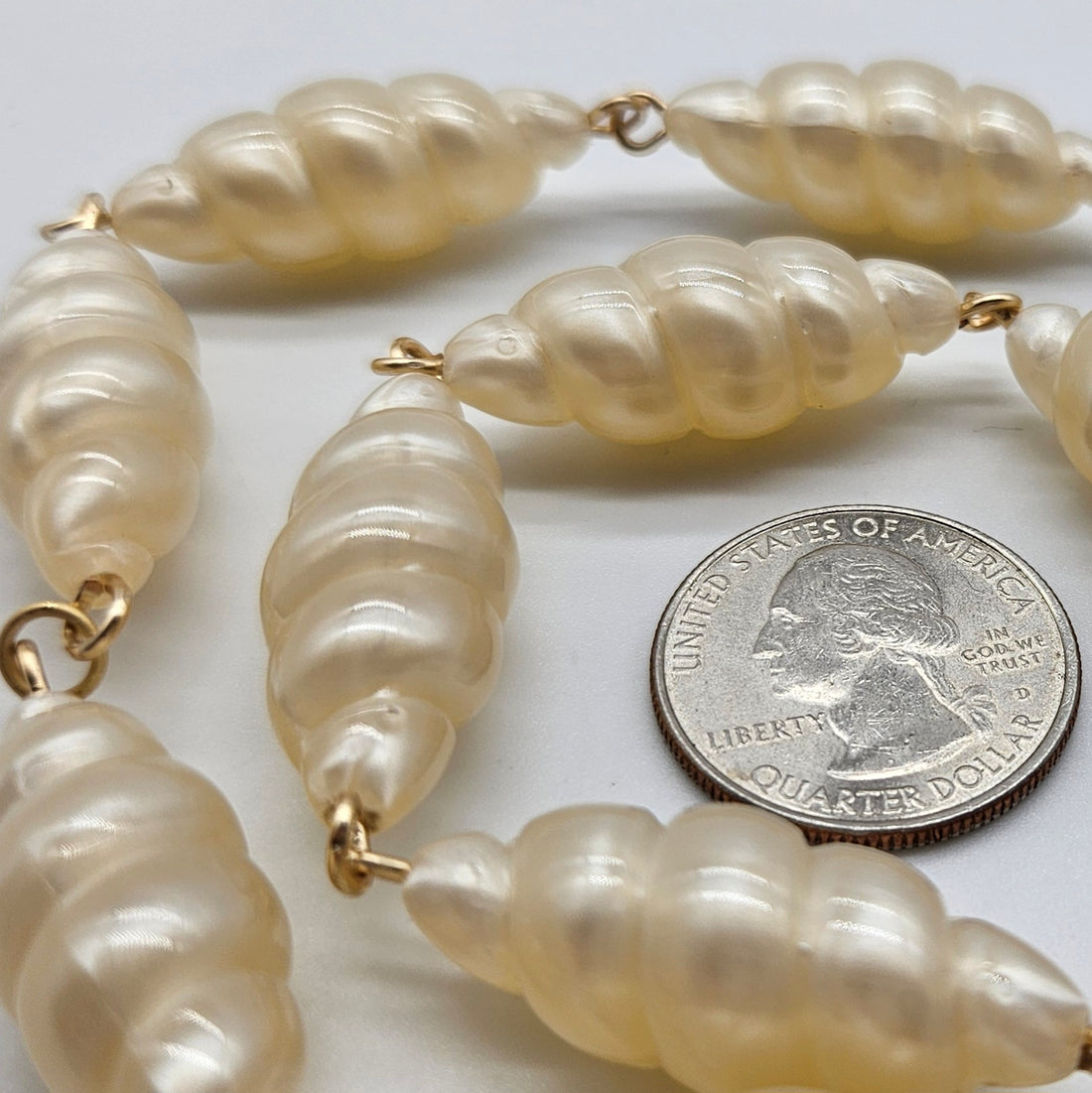 Lucite necklace with a quarter for scale on a white background