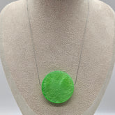 Green circular pendant on a gray fabric background