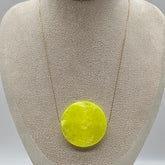 Necklace with a round, yellow pendant on a gray bust