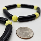 Black and yellow beaded brcelet next to a quarter for size reference on a white background