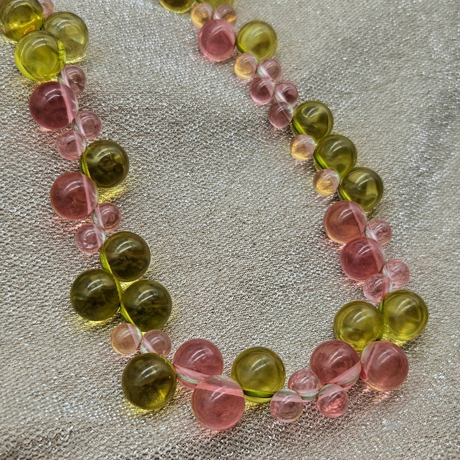 Necklace with green and pink beads on a textured surface