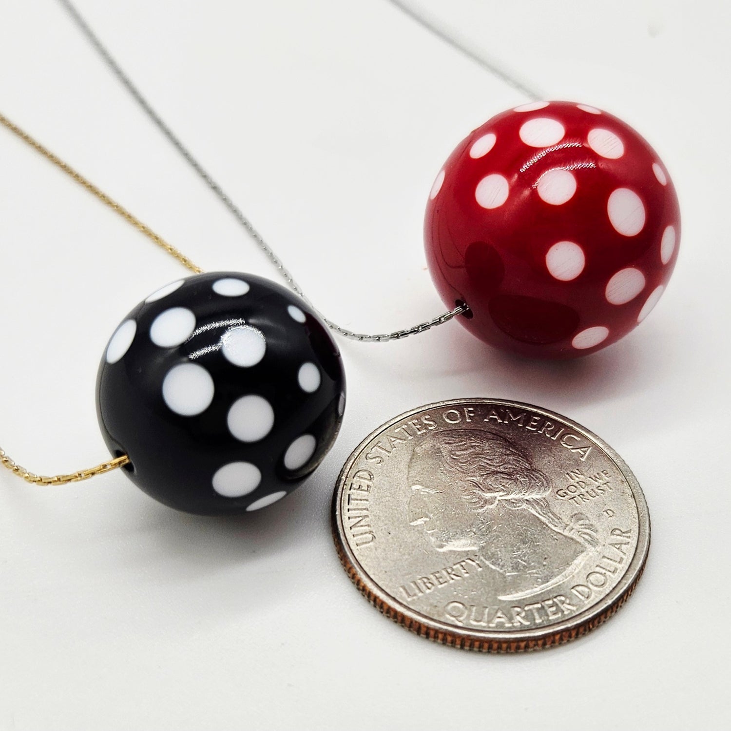 Black and red polka dot beads with a quarter on a white background