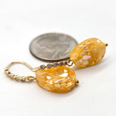 Gold earrings with a quarter for scale on a white background
