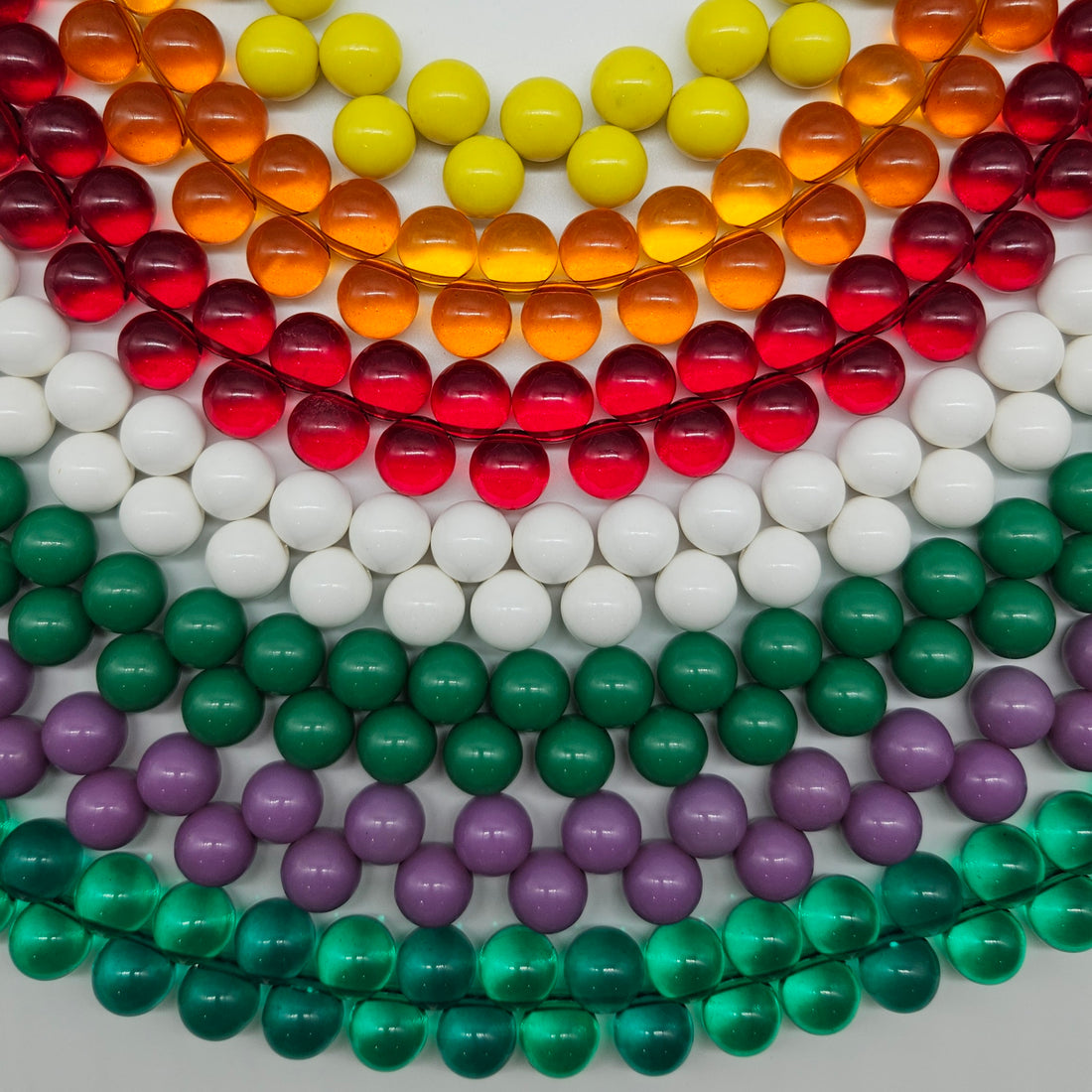 Multiple colorful beaded necklaces laid out on a white background.