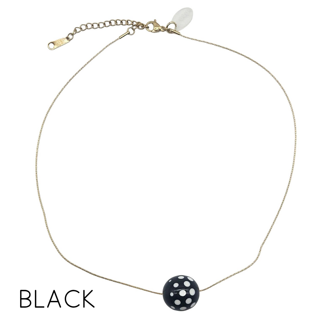 Necklace with a black and white polka dot pendant on a white background