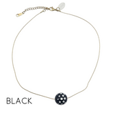 Necklace with a black and white polka dot pendant on a white background
