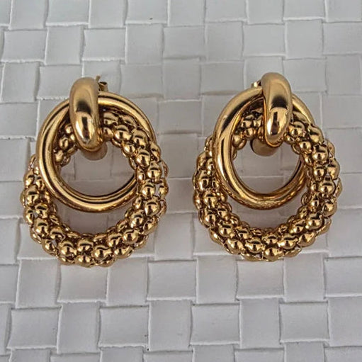 Pair of gold hoop earrings on a textured gray background