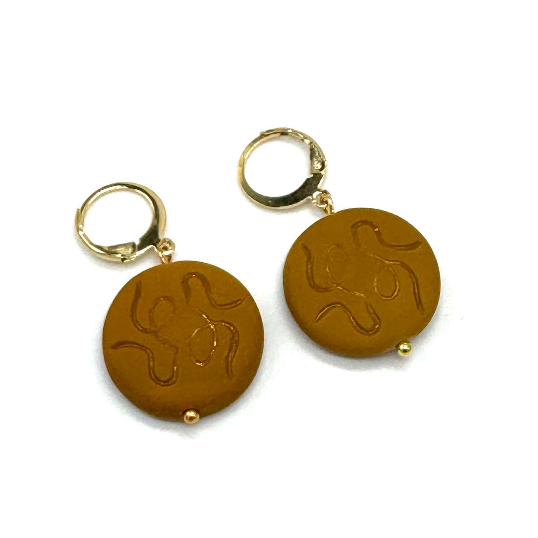 Pair of gold earrings with circular brown stones featuring embossed designs on a white background.
