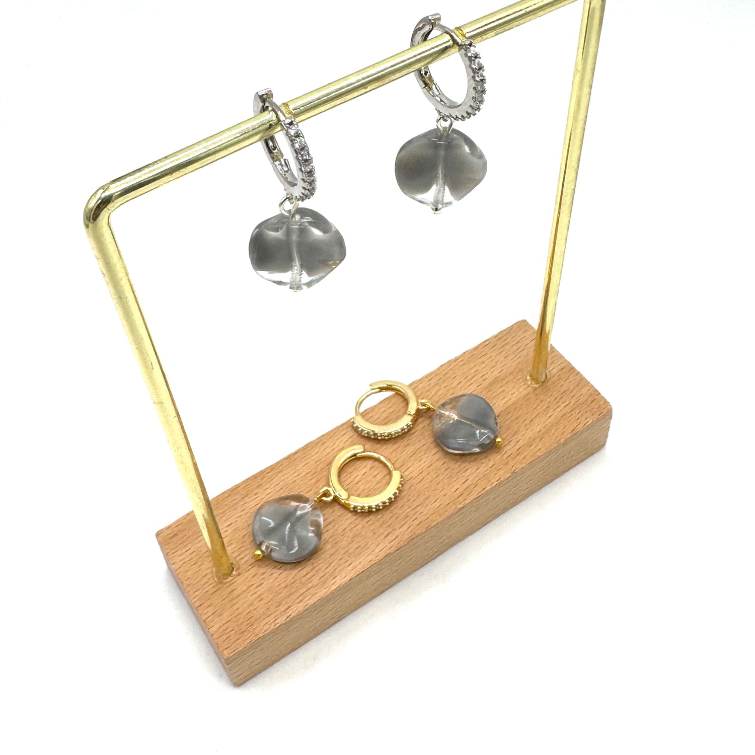 Earrings on a gold and wooden stand against a white background