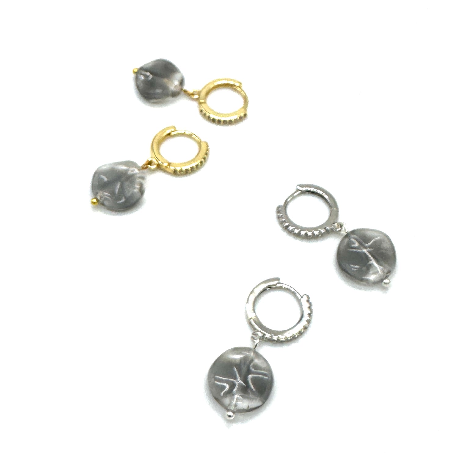 Set of silver and gold hoop earrings with engraved designs on a white background