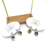 Pair of earrings on display with a branded card on a white background