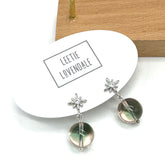 Pair of earrings with star designs on a white card with &