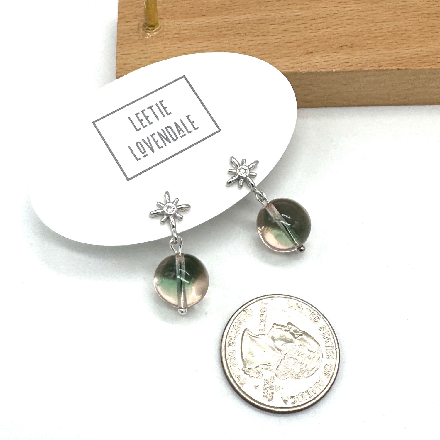 Pair of earrings with star and round stone design on a white card with &