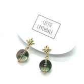 Gold earrings with green stones on a white background with &