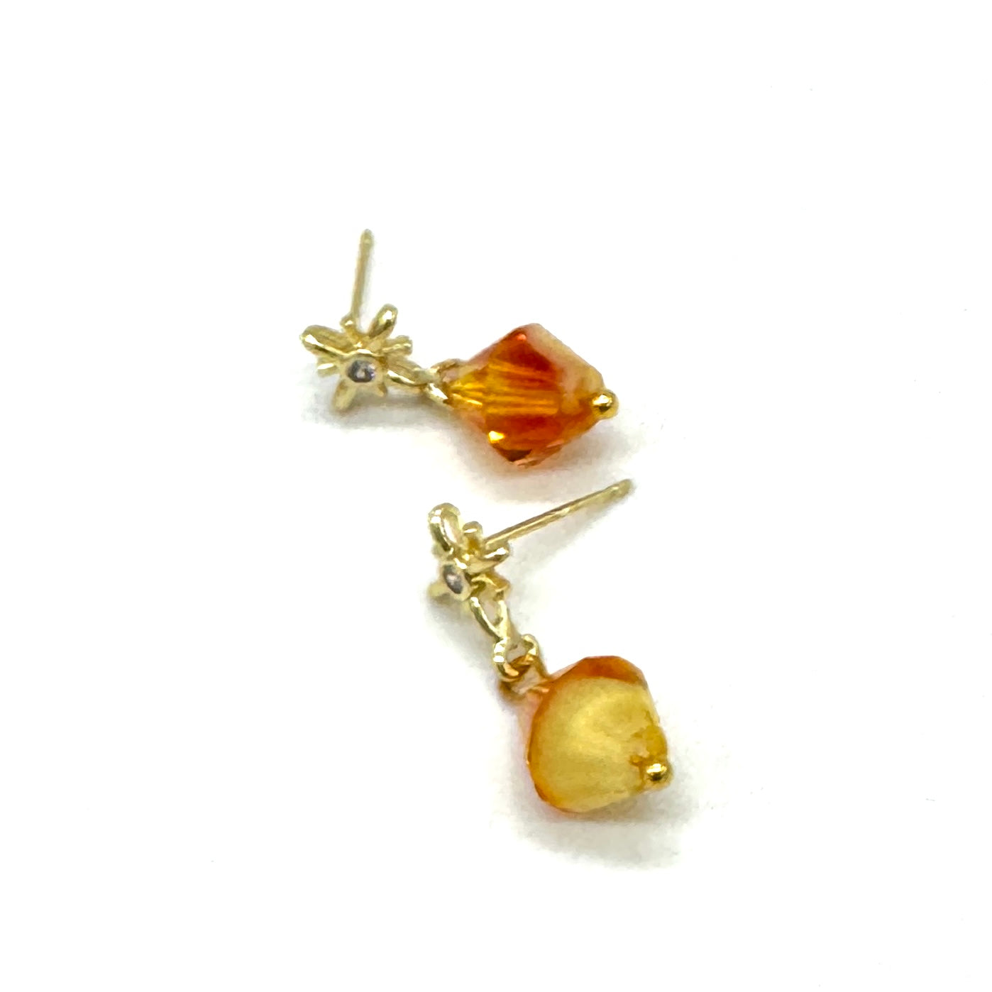 Gold earrings with amber-colored beads on a white background