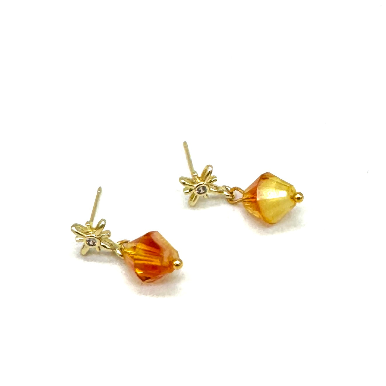 Gold earrings with amber-colored beads on a white background