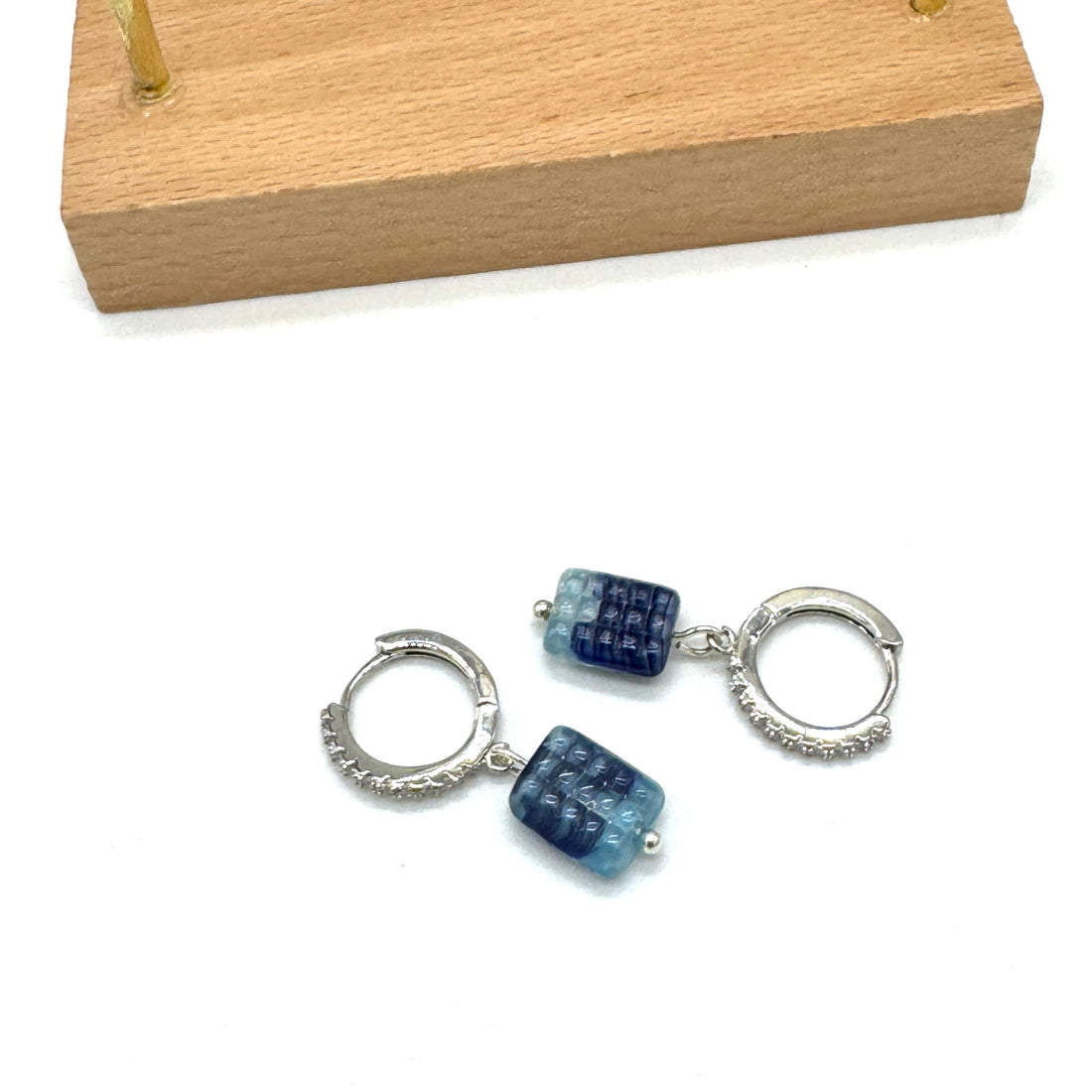 Silver hoop earrings with blue gemstones on a white background