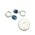 Pair of silver hoop earrings with blue gemstones next to a quarter for scale on a white background