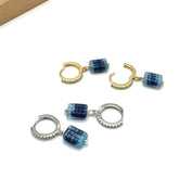 Pair of hoop earrings with blue cube beads on a white background