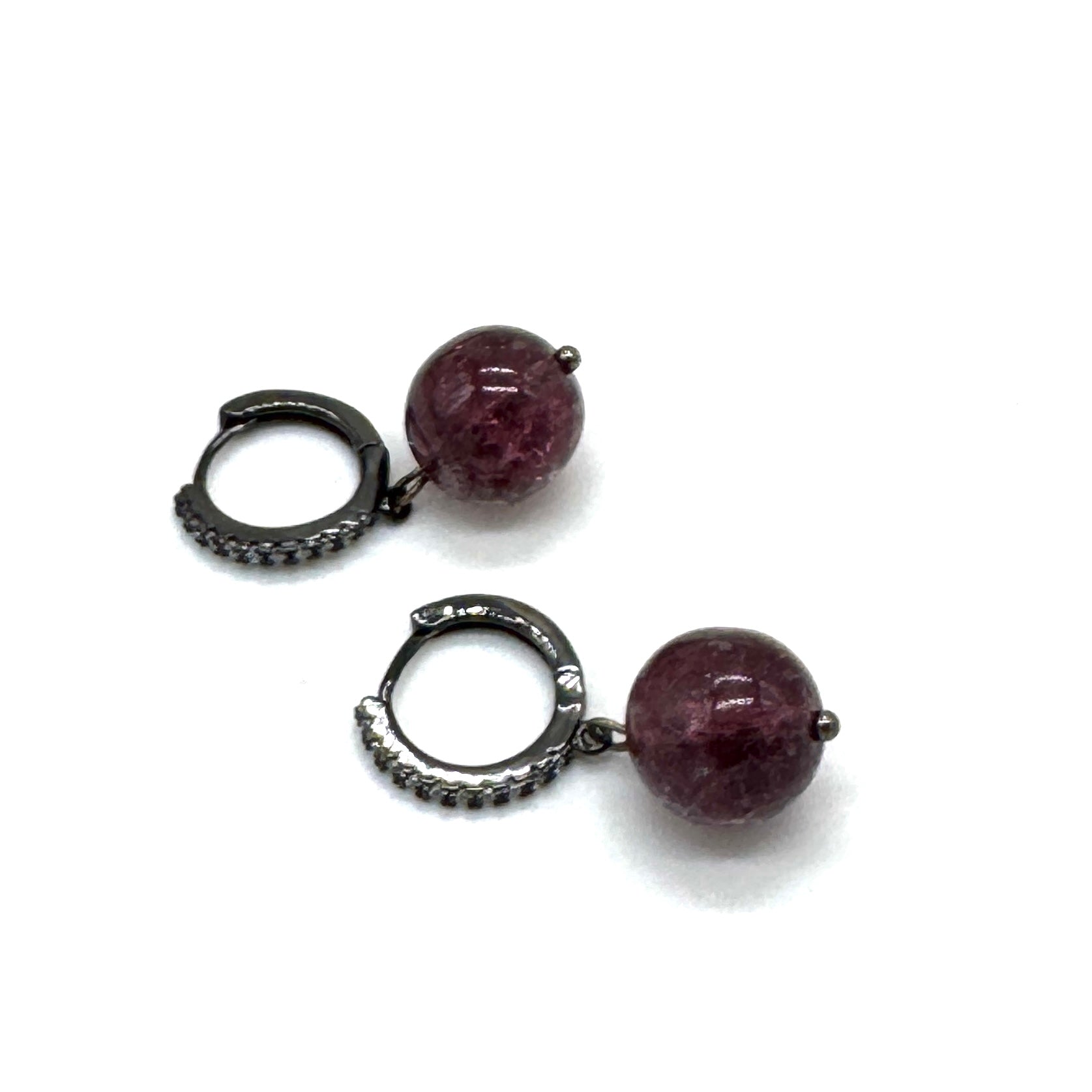 Pair of earrings with purple beads and silver hooks on a white background