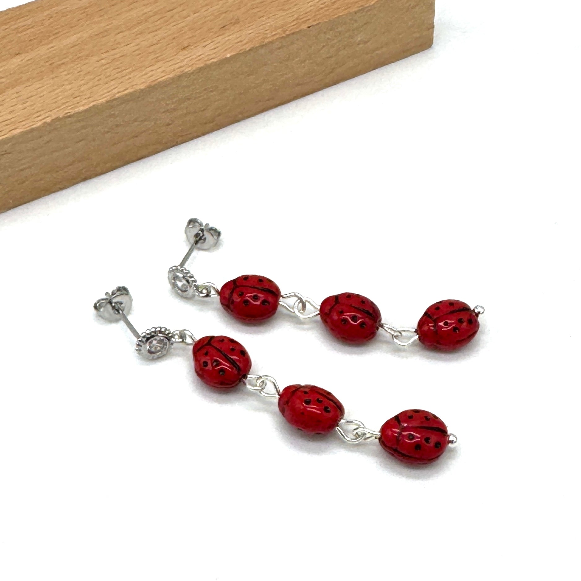 Red beaded earrings with silver accents on a white surface