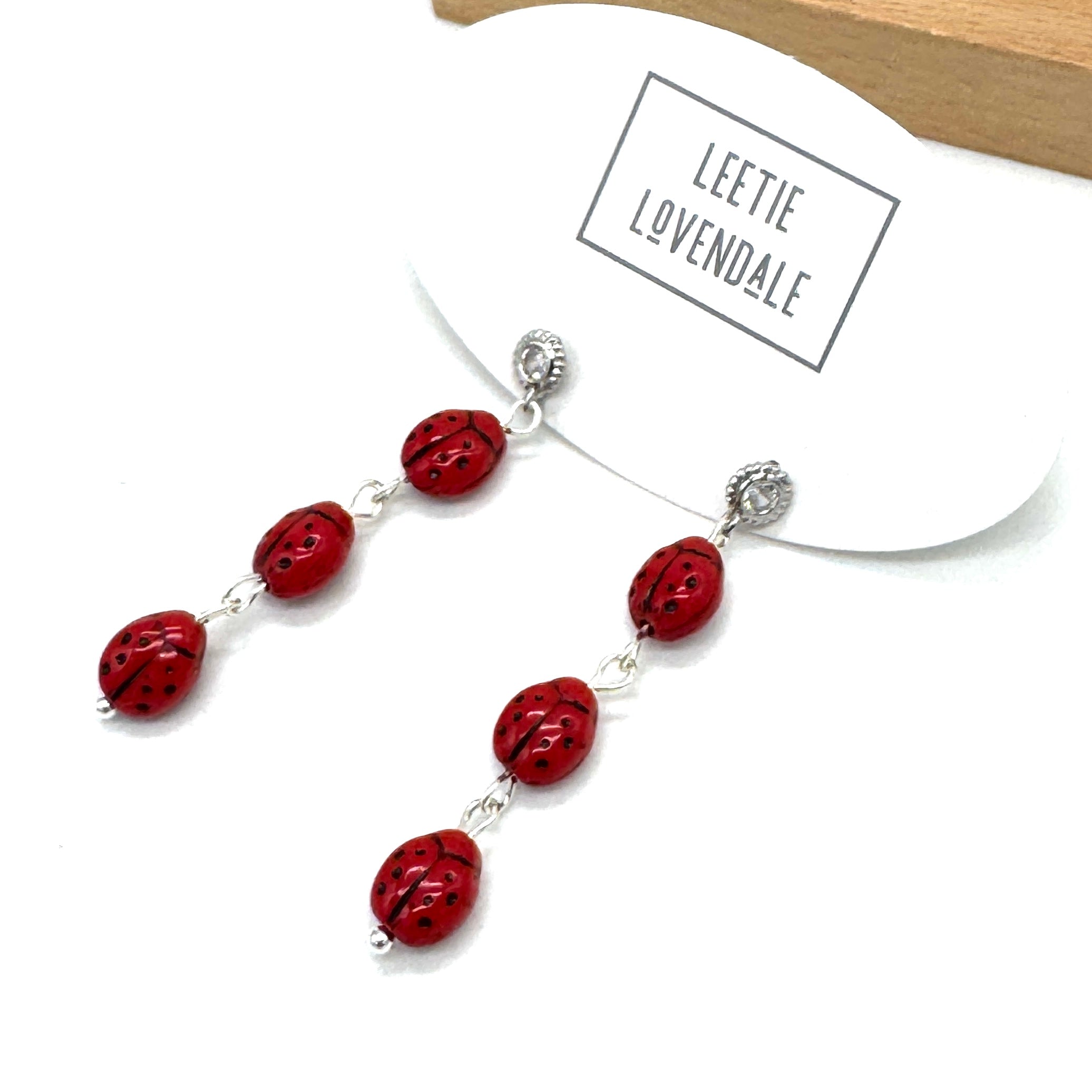 Necklace with red beads and silver clasps on a white card with &