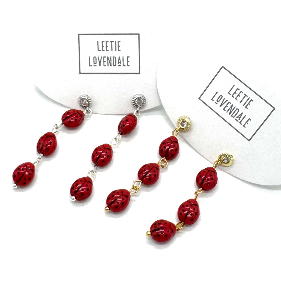 Red beaded earrings with gold accents on a white background, branded &