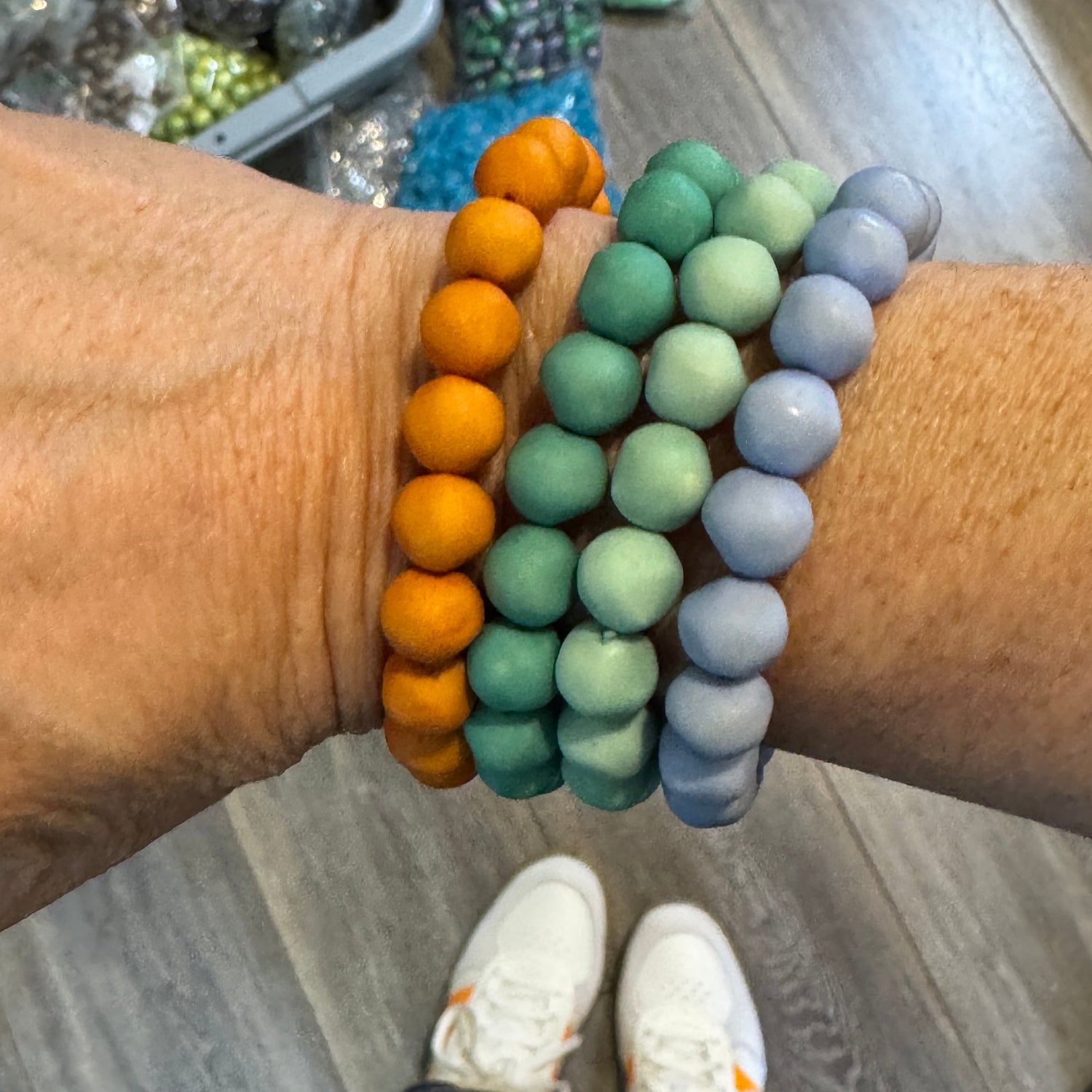 Set of four lucite beaded bracelets in orange, teal, turquoise, and periwinkle worn on a wrist